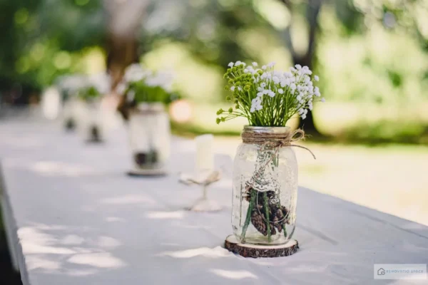 Mason jar filled with water and fresh herb stems as a kitchen table centerpiece