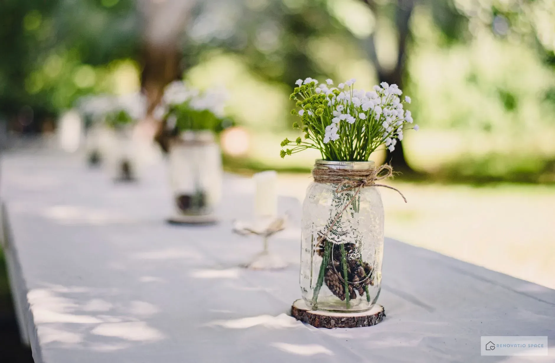 Mason jar filled with water and fresh herb stems as a kitchen table centerpiece