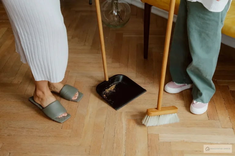 Parent sweeping a light-colored vinyl floor in a children's room with toys