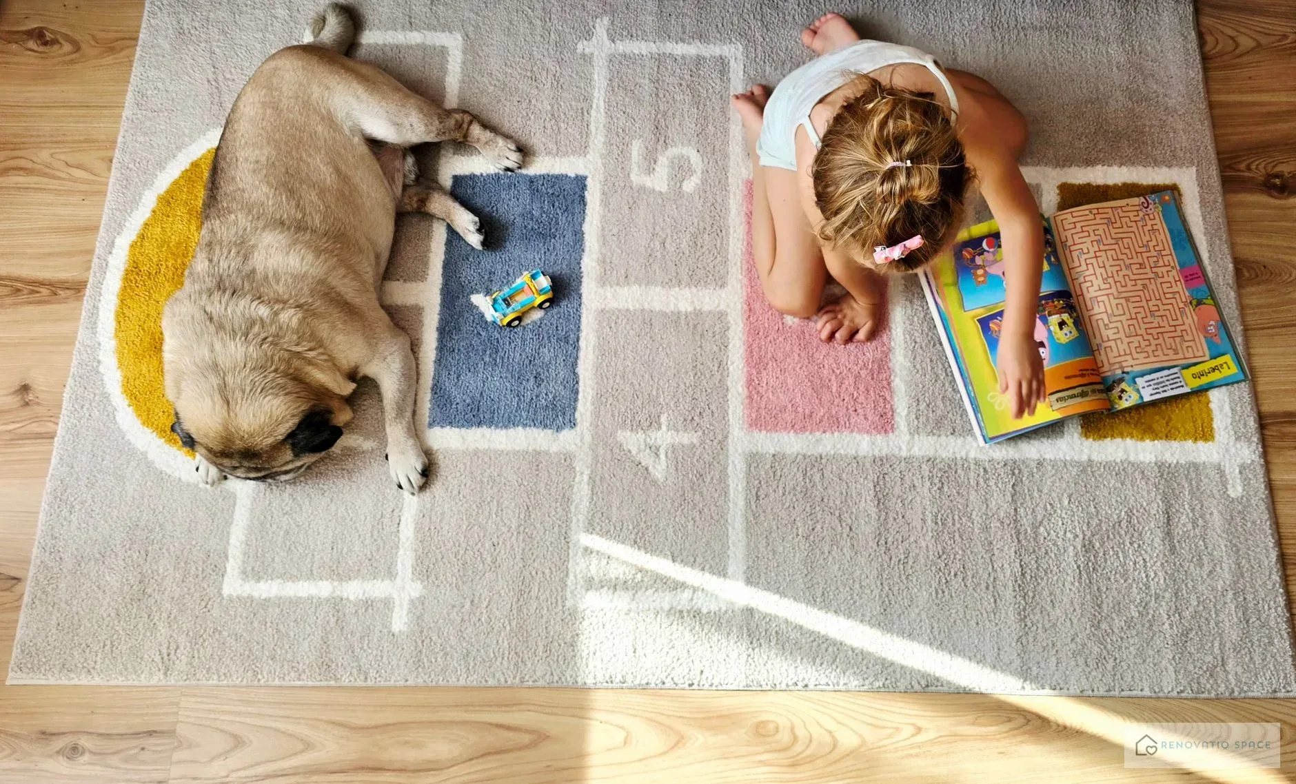 Hund und Kind sitzen zusammen auf einem Vinylboden in Holzoptik in einem hellen Kinderzimmer
